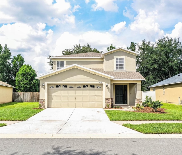 traditional home with a front lawn, fence, concrete driveway, stucco siding, and stone siding