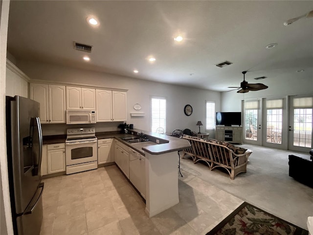 kitchen with white appliances, white cabinetry, sink, kitchen peninsula, and ceiling fan