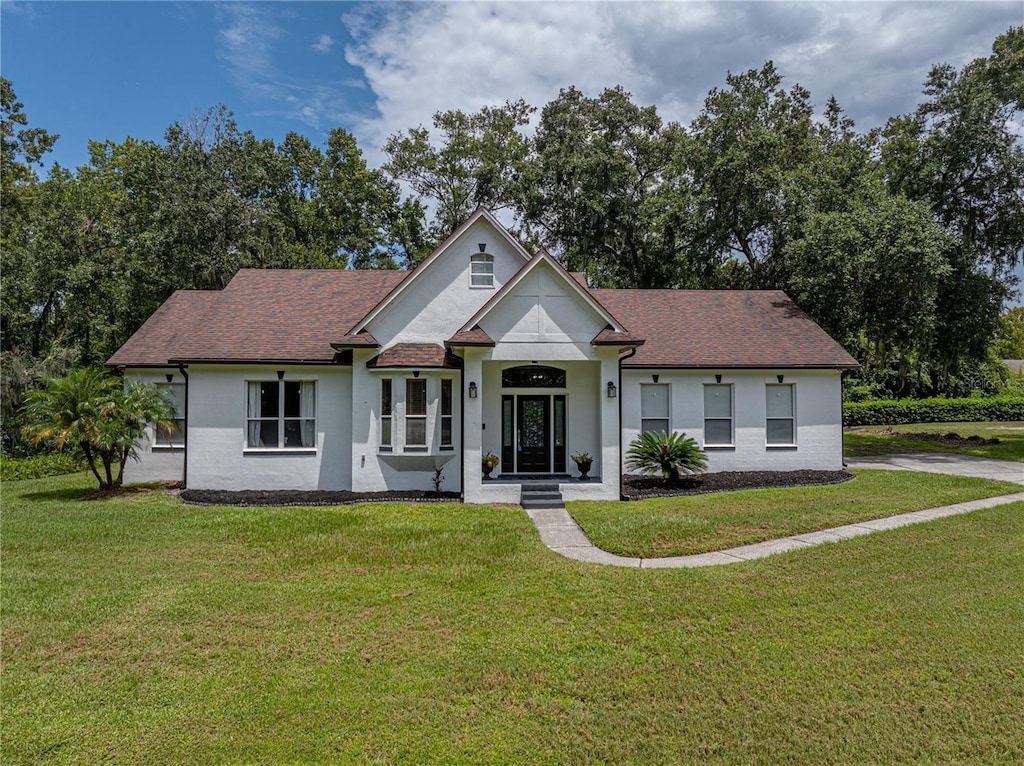 view of front facade featuring a shingled roof and a front lawn