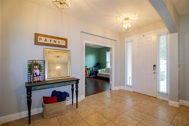 entrance foyer featuring arched walkways, plenty of natural light, baseboards, and light tile patterned floors