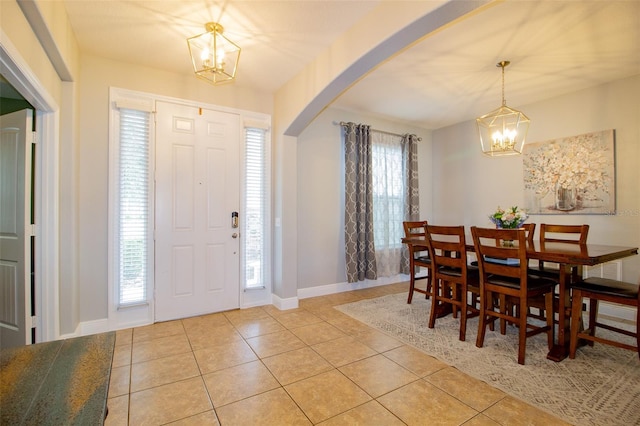 entryway with a healthy amount of sunlight, a chandelier, arched walkways, and light tile patterned flooring