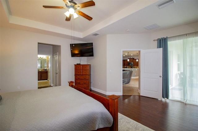 bedroom featuring a raised ceiling, visible vents, baseboards, and wood finished floors