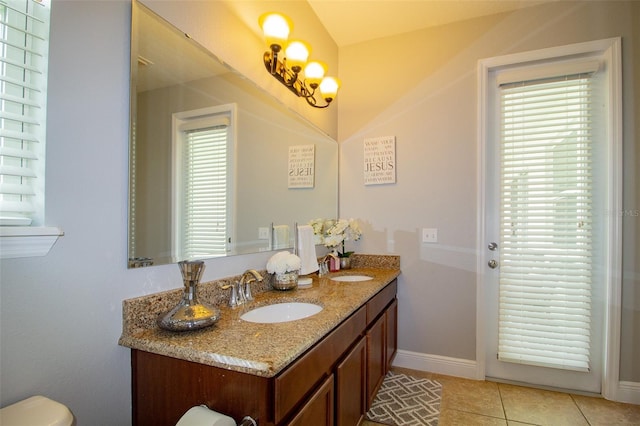 bathroom with double vanity, baseboards, a sink, and tile patterned floors