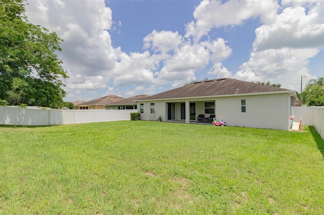 rear view of house featuring a lawn, a patio area, a fenced backyard, and stucco siding