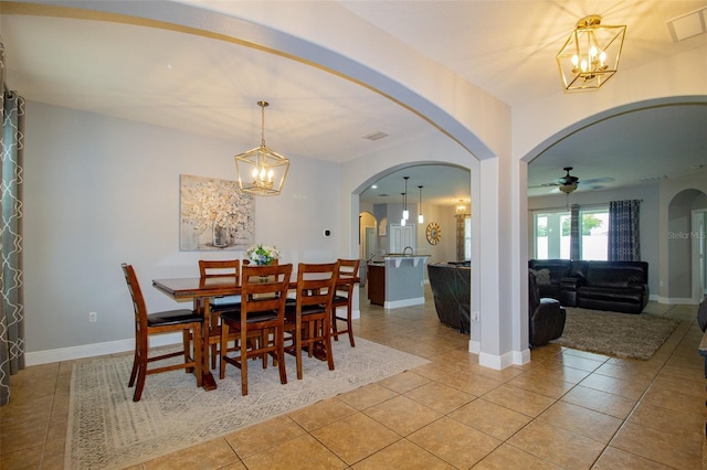 dining area featuring arched walkways, baseboards, and light tile patterned floors