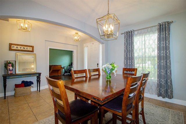 dining room featuring light tile patterned floors, baseboards, arched walkways, and a notable chandelier