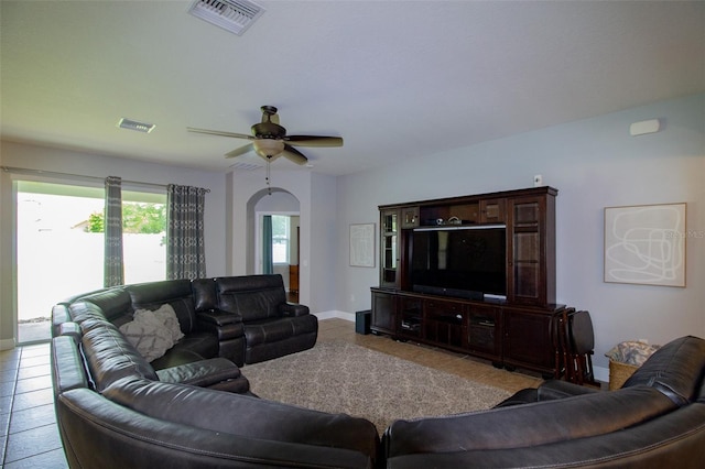 tiled living room with arched walkways, ceiling fan, visible vents, and baseboards