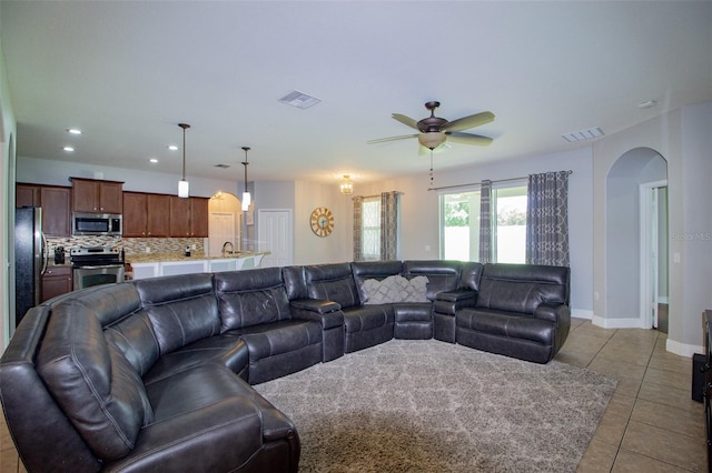 living area featuring light tile patterned floors, arched walkways, recessed lighting, visible vents, and baseboards