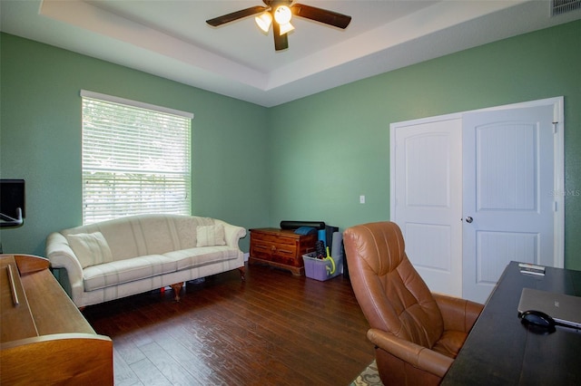 office space featuring a ceiling fan, a raised ceiling, visible vents, and wood finished floors