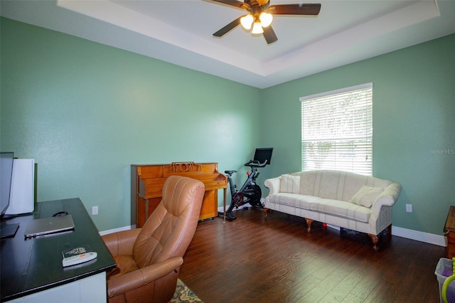 office space with baseboards, a tray ceiling, ceiling fan, and wood finished floors