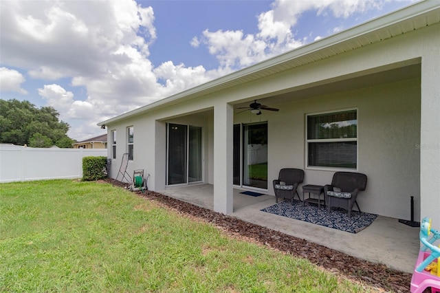 exterior space with stucco siding, a lawn, a ceiling fan, a patio area, and fence