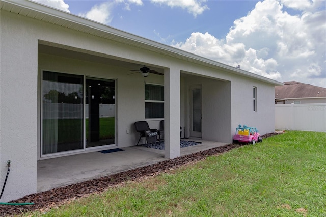 rear view of house with a yard, a patio, stucco siding, ceiling fan, and fence