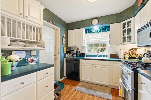 kitchen featuring backsplash, light hardwood / wood-style floors, white cabinetry, sink, and black appliances