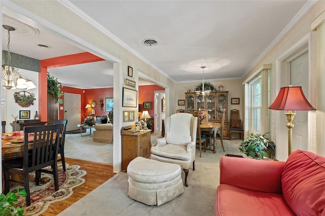 living room with ornamental molding, hardwood / wood-style flooring, and an inviting chandelier