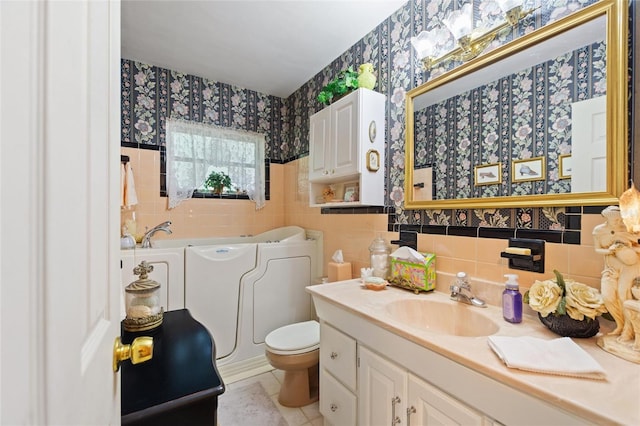 bathroom featuring a tub, vanity, tile patterned flooring, tile walls, and toilet