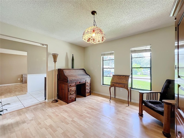 living area with light wood-style floors, a textured ceiling, and baseboards