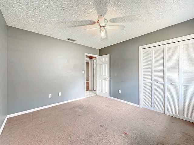 unfurnished bedroom with light carpet, visible vents, baseboards, a textured ceiling, and a closet