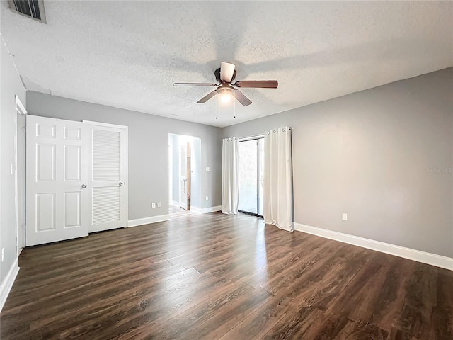 interior space featuring baseboards, visible vents, ceiling fan, dark wood-type flooring, and a textured ceiling