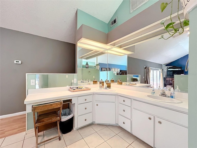 full bathroom with vaulted ceiling, a textured ceiling, tile patterned flooring, and a sink