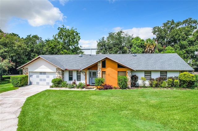 view of front facade featuring a garage, a shingled roof, concrete driveway, stone siding, and a front yard