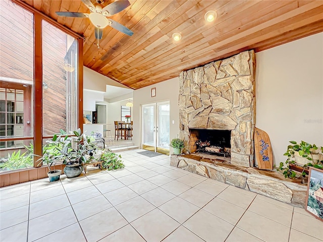 unfurnished living room featuring light tile patterned floors, wood ceiling, a stone fireplace, vaulted ceiling, and french doors