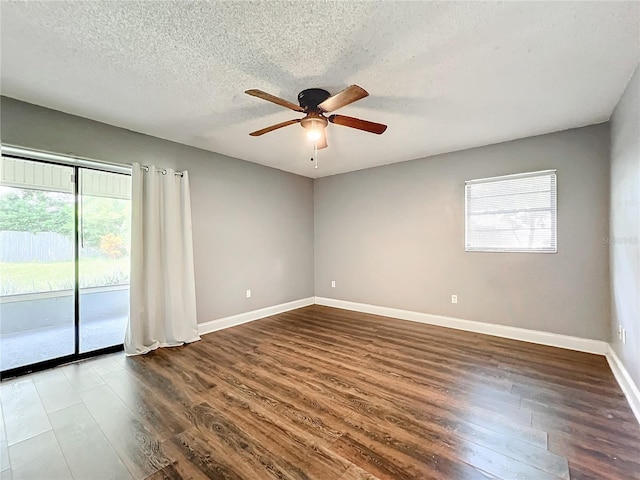 empty room with a textured ceiling, baseboards, dark wood finished floors, and a ceiling fan