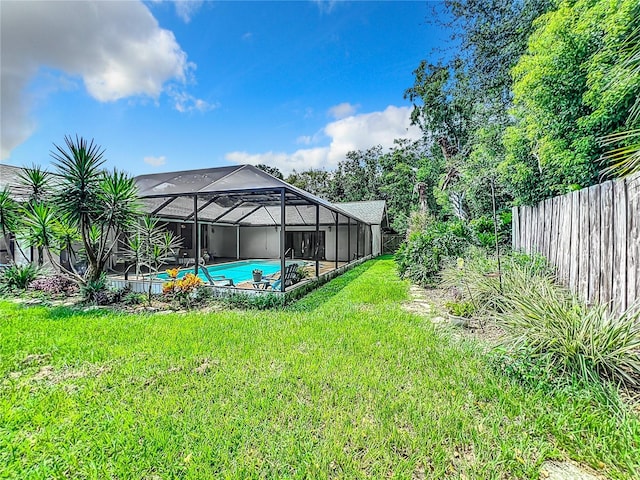 view of yard with glass enclosure, fence, and an outdoor pool