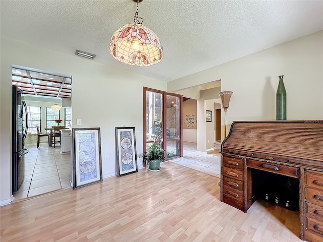 office space with baseboards, light wood-style flooring, visible vents, and a textured ceiling