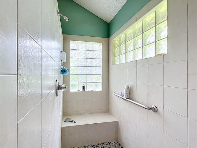 full bathroom featuring a textured ceiling, tiled shower, and lofted ceiling