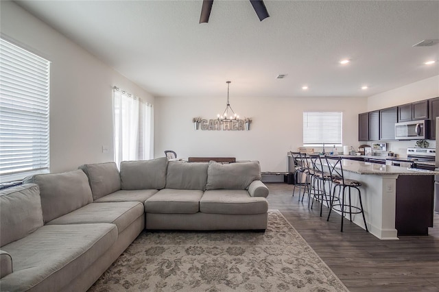 living room featuring ceiling fan with notable chandelier and hardwood / wood-style floors