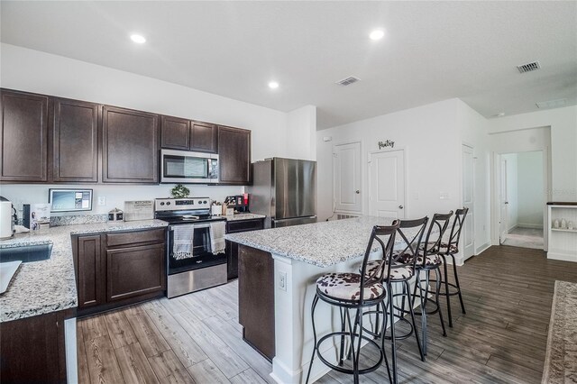 kitchen featuring wood-type flooring, a kitchen breakfast bar, stainless steel appliances, and a center island