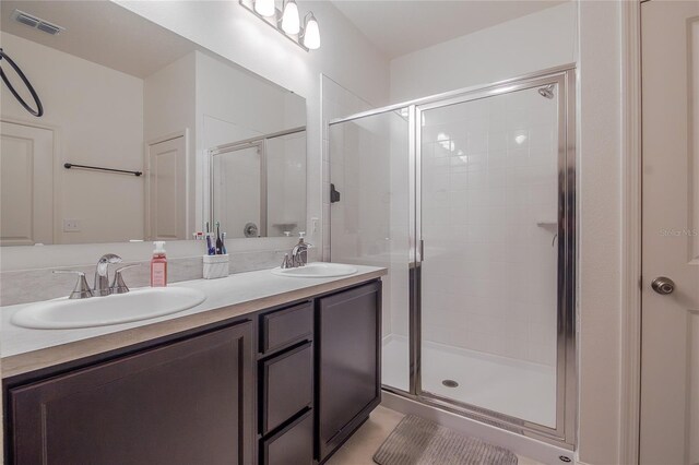 bathroom with an enclosed shower, dual bowl vanity, and tile patterned flooring