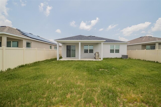 back of house featuring cooling unit, a patio, solar panels, and a yard