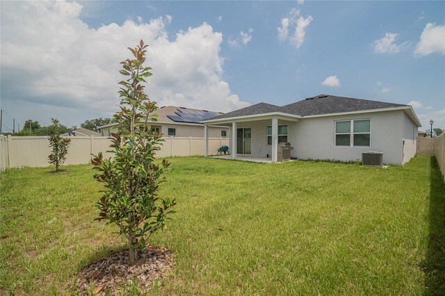 rear view of property with central AC, solar panels, a yard, and a patio area