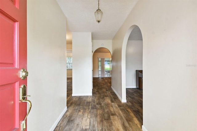 entryway featuring dark wood-style floors, arched walkways, and baseboards