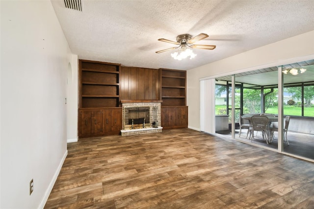 unfurnished living room with a textured ceiling, a fireplace, visible vents, and dark wood-style flooring