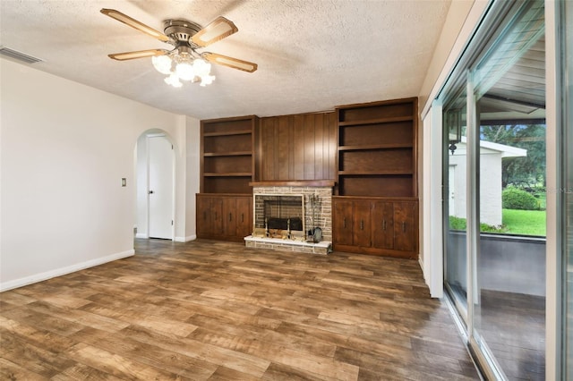 unfurnished living room with dark wood-type flooring, arched walkways, visible vents, and a textured ceiling