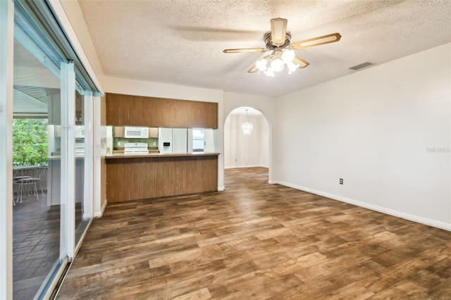 kitchen with white appliances, visible vents, arched walkways, brown cabinets, and a peninsula