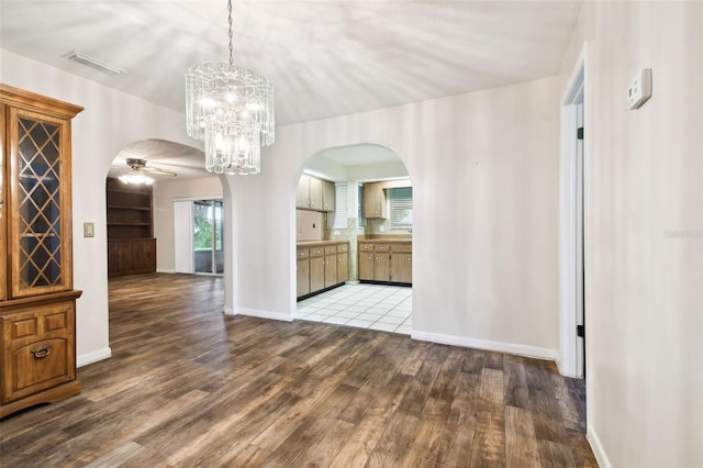 unfurnished dining area featuring arched walkways, light wood finished floors, visible vents, and baseboards