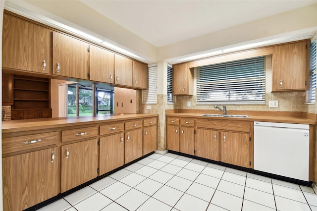 kitchen featuring brown cabinetry, light countertops, white dishwasher, and a sink