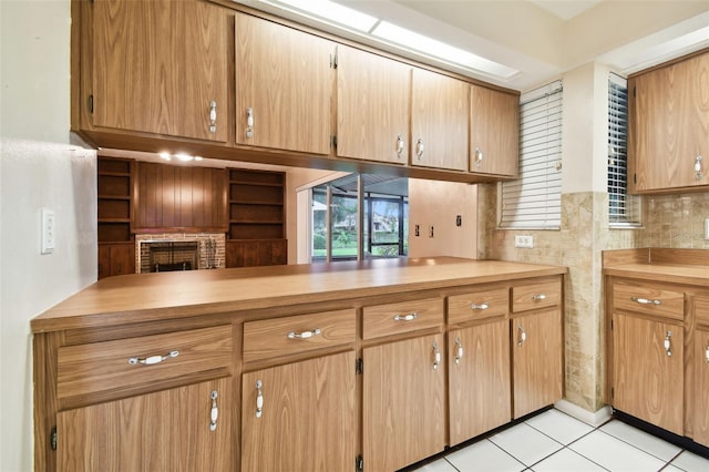 kitchen with a fireplace, light countertops, open floor plan, light tile patterned flooring, and a peninsula