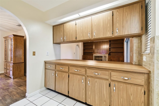 kitchen with light wood-style floors, baseboards, arched walkways, and light countertops