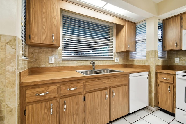 kitchen with tasteful backsplash, white appliances, light countertops, and a sink