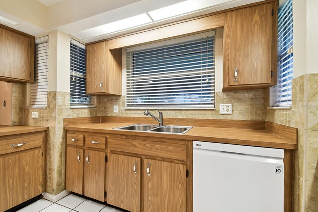 kitchen with light tile patterned floors, tasteful backsplash, dishwasher, light countertops, and a sink