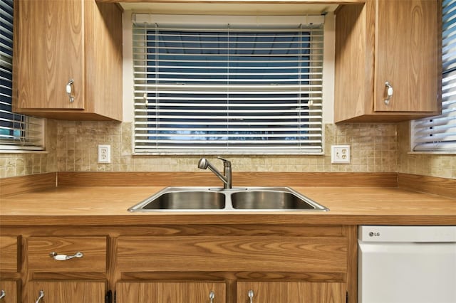 kitchen with dishwasher, decorative backsplash, a sink, and brown cabinets