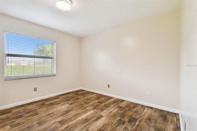 spare room featuring dark wood-style floors, a textured ceiling, and baseboards