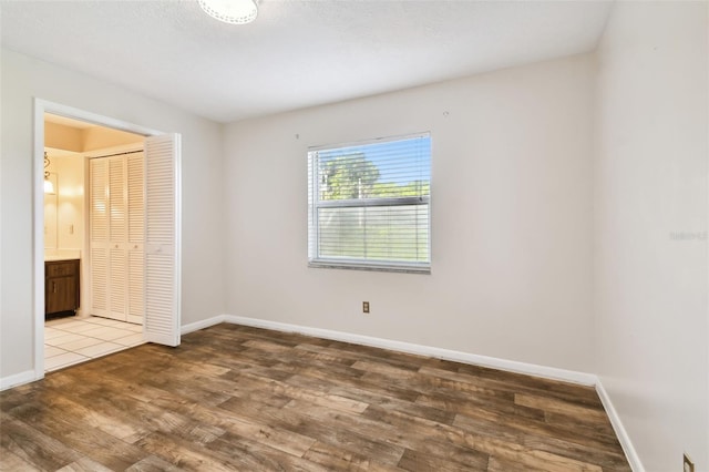 unfurnished bedroom featuring a closet, wood finished floors, and baseboards