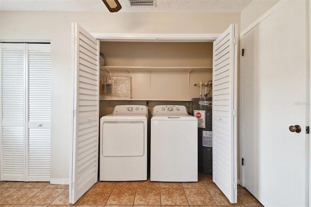 washroom with laundry area, a textured ceiling, water heater, separate washer and dryer, and light tile patterned flooring