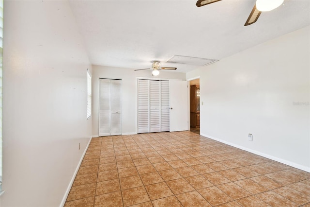 unfurnished bedroom with light tile patterned floors, two closets, a ceiling fan, and baseboards