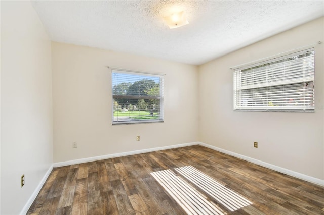 unfurnished room featuring dark wood-style floors, baseboards, and a textured ceiling